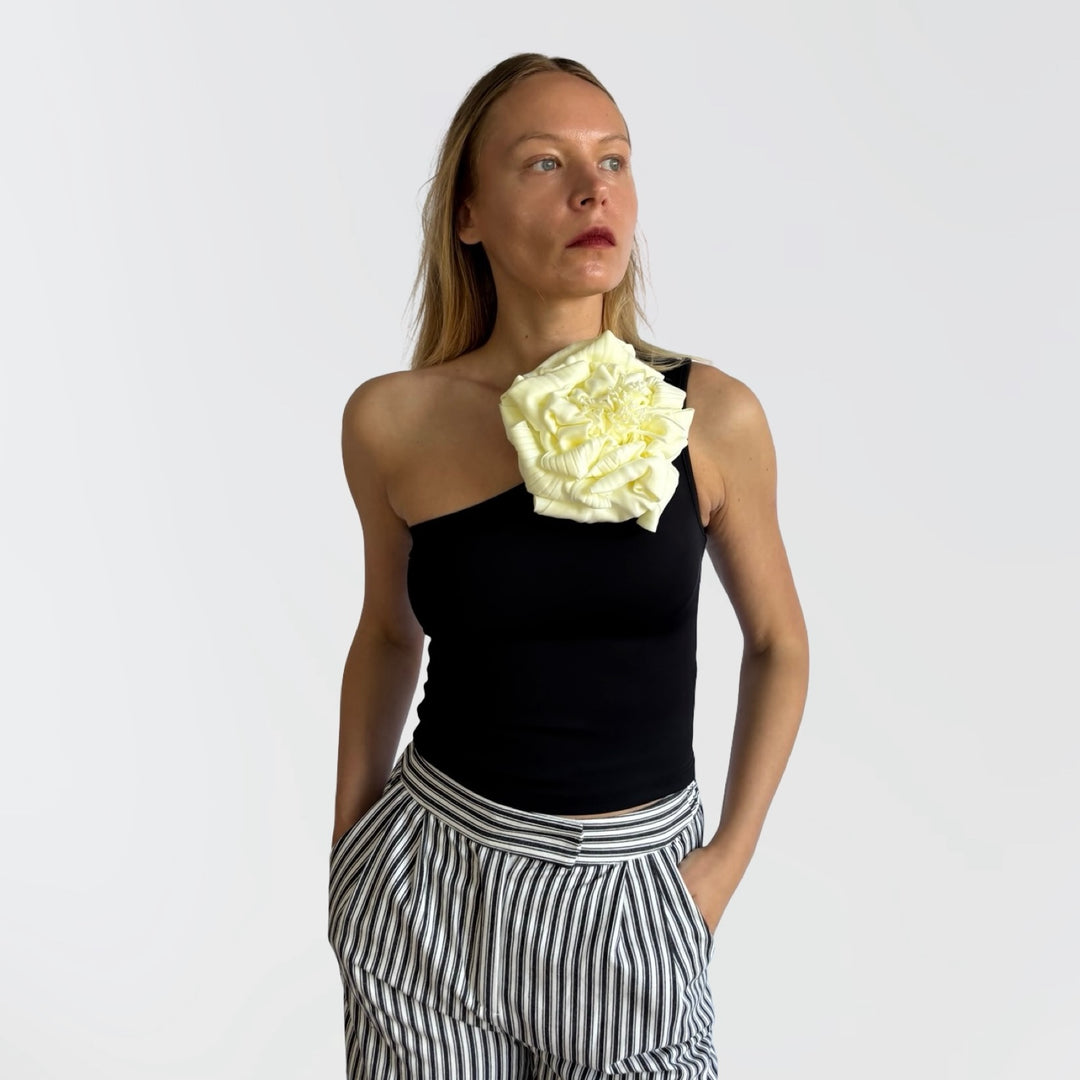 Black one shoulder top with white flower pin